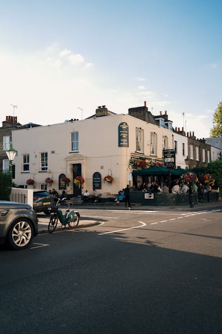 The image shows a charming two-story building on Chiswick High Road, featuring light-colored exterior walls and classic architectural details. The ground floor appears to house a cafe or pub, with out